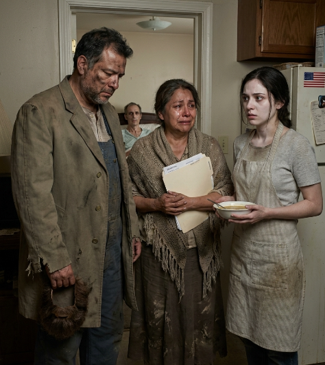 WHEN THE RICH PARENTS DRESSED LIKE BEGGARS TO TEST THEIR CHILDREN, THEY NEVER EXPECTED THE DAUGHTER-IN-LAW THEY DESPISED TO OPEN THE DOOR — OR TO FIND THEIR DYING SON HIDDEN INSIDE  They came to judge kindness.  They found their son dying.  And the woman they hated was the only one who had stayed.  Don Ernesto Álvarez stood in the doorway of the small house with rain dripping from the brim of his dirty cap, his fake beard itching against his face, and shame slowly crawling up his spine.  Behind him, his wife, Doña Carmen, clutched the torn shawl around her shoulders. Mud stained the bottom of her skirt. Her hands trembled, not from the cold anymore, but from the weak voice that had just come from the back room.  “Mariana?” the voice called. “Are they here?”  Ernesto stopped breathing.  For eight months, he had told himself his youngest son, Rafael, had become ungrateful. Proud. Poisoned by the poor wife who had “stolen” him from the Álvarez family. He had imagined Rafael laughing somewhere, healthy and stubborn, refusing to call because Mariana had filled his head with resentment.  But that voice was not proud.  It was barely alive.  Mariana moved in front of the hallway, flour and sauce still smudged on her cheek from the dinner she had been preparing. Her face had gone pale, but her eyes stayed fixed on the two strangers she had just welcomed out of the rain.  “Please,” she whispered. “Don’t go in like that.”  Ernesto looked down at himself.  The torn coat. The muddy pants. The dirt he had rubbed into his own hands to see which of his children would recognize his soul when his wealth disappeared.  The test had felt clever that morning.  Now it felt filthy.  “Move,” he said, but his voice had lost its command.  Mariana shook her head.  “Not until you tell me who you really are.”  Doña Carmen made a broken sound behind him. She had already heard Rafael’s voice. Already seen the folder on the table with her name written across hospital papers. Already begun to understand that the daughter-in-law she once called a stain was standing between them and a truth their mansion had refused to see.  Slowly, Ernesto reached up and pulled off the fake beard.  Mariana’s eyes widened.  Then Carmen pulled the shawl from her head, and the proud old woman beneath the costume appeared with tears running down her face.  Mariana stared at them.  Not with surprise for long.  With hurt.  Deep, quiet hurt.  “So it was a test,” she said.  No one answered.  From the back room, Rafael coughed.  The sound tore through the little house.  Mariana turned instantly toward him, her whole body alert, protective, exhausted. Then she looked back at Ernesto and Carmen.  “Wash your hands first,” she said. “He gets infections easily.”  That was the moment Ernesto almost fell apart.  Not because she insulted him.  Because even now, after all they had done to her, she was still protecting his son before punishing his parents.  At the kitchen sink, Ernesto scrubbed the mud from his hands. The water ran brown, then clear, circling the drain like pride finally coming off skin. Carmen washed beside him, crying silently.  Mariana handed them towels.  Old.  Thin.  Clean.  Then she led them down the narrow hallway.  The room smelled of medicine, damp blankets, and something fragile. On a small table sat pharmacy bottles, folded receipts, a plastic cup with a straw, and a notebook full of dates and numbers. A fan turned slowly in the corner.  Rafael lay in the bed, thinner than any father should ever see his son.  His cheeks were hollow. His skin had a grayness that no young man should carry. An oxygen tube rested beneath his nose. His wedding band hung loose on his finger.  When he saw them, his eyes filled.  “Papá,” he whispered.  Carmen covered her mouth and stumbled toward the bed.  Ernesto stood frozen in the doorway.  He remembered Rafael as a boy racing through the warehouse, jumping over boxes, shouting that one day he would run the family business better than anyone. He remembered carrying him through the market while Rafael pointed at mangoes and balloons, wanting everything from life.  Now his son looked like life had been taken from him one bill at a time.  “What happened?” Ernesto asked.  Rafael tried to smile.  “You finally came.”  Carmen fell beside the bed, kissing his hand, his wrist, his forehead, saying his name like prayer could rebuild flesh.  Ernesto stepped closer.  “What happened to you?”  Rafael closed his eyes. “Kidneys first. Then the infection. Then surgery complications.” He breathed slowly. “It got expensive.”  Ernesto turned to Mariana.  “Why didn’t you call us?”  She did not flinch.  “I did.”  The room went silent.  Mariana opened a drawer and pulled out a notebook. She placed it in Ernesto’s hands.  He read the first page.  Calls to Claudia. No answer.  Message to Gustavo. Seen.  Voice note to Doña Carmen. Deleted.  Visit to main house. Gate refused entry.  His stomach turned cold.  Mariana had not kept Rafael from them.  Their other children had.  Carmen shook her head. “No. I would have known.”  Mariana’s eyes shone, but her voice stayed calm. “You changed your number after the wedding. Claudia said I was not allowed to contact you unless Rafael apologized for marrying me.”  The wedding.  The day Ernesto had refused to attend.  The day Carmen said Mariana would never sit at the Álvarez table.  The day Rafael walked away with his wife, and they called it betrayal because it was easier than calling it courage.  On the table, Ernesto noticed a folder half-hidden under receipts.  Carmen saw her own name on one page.  “What is that?” she whispered.  Rafael opened his eyes. “Don’t.”  But Ernesto had already reached for it.  Inside were hospital bills.  Bank transfers.  Pharmacy receipts.  Then he saw the deposits.  Monthly payments sent to his and Carmen’s household account for years.  Not from Gustavo.  Not from Claudia.  From Rafael.  The son they called ungrateful had been paying for their medicine, repairs, groceries, and comfort while lying sick in a poor house with chipped bowls and unpaid bills.  Carmen began to shake.  “Gustavo said he sent that money.”  Mariana looked down.  “He took credit.”  Ernesto turned to Rafael.  “Why?”  Rafael’s smile was weak, but the answer destroyed the room.  “Because you were still my parents.”  No one moved.  No one spoke.  The rain tapped the roof softly, as if even the sky knew to lower its voice.  Ernesto reached into his sock and pulled out the gold family ring he had hidden there — the prize he had planned to give whichever child passed his little test of kindness.  Now it looked ridiculous in his palm.  Small.  Cold.  Worthless.  Rafael looked at it and understood.  “You were testing them?”  Ernesto closed his fist around the ring.  “Yes.”  “And?”  Ernesto looked toward the kitchen, where Mariana had left two warm bowls of soup for two strangers she thought had nowhere to go.  His voice broke.  “I failed first.”  Mariana looked away.  Carmen reached for her. “Hija…”  Mariana stepped back.  “No.”  The word was soft, but it closed a door.  “I don’t get to be hija now,” she said, “just because you found out I was useful.”  Carmen’s hand fell.  Ernesto wanted to defend his wife, but he couldn’t. Mariana was right. They had hated her when she had nothing to offer their pride. Now that she had fed, nursed, protected, and saved their son, they wanted to call her family.  But family was not a title to be handed out when the truth became embarrassing.  It was something they should have protected long ago.  Mariana turned back to Rafael and lifted the cup to his lips with hands so tired they trembled. He drank a little. She wiped the corner of his mouth with the edge of a cloth.  The tenderness between them filled the room with everything the Álvarez mansion had never understood.  Ernesto placed the ring on the table beside Rafael’s bed.  “I came tonight to decide who deserved the Álvarez name,” he said quietly.  Mariana looked at him.  He swallowed hard.  “But now I see the name does not deserve you.”  For the first time, her face nearly broke.  Nearly.  Then Rafael coughed again, and she straightened because women like Mariana had learned that tears could wait, but medicine could not.  Ernesto looked at his son’s thin hand, at the receipts, at his wife’s trembling shoulders, at the daughter-in-law they had judged from behind gates and polished windows.  Then Mariana said, very softly, “He needs rest.”  And as Ernesto stepped back into the hallway, he realized the test had only just begun…